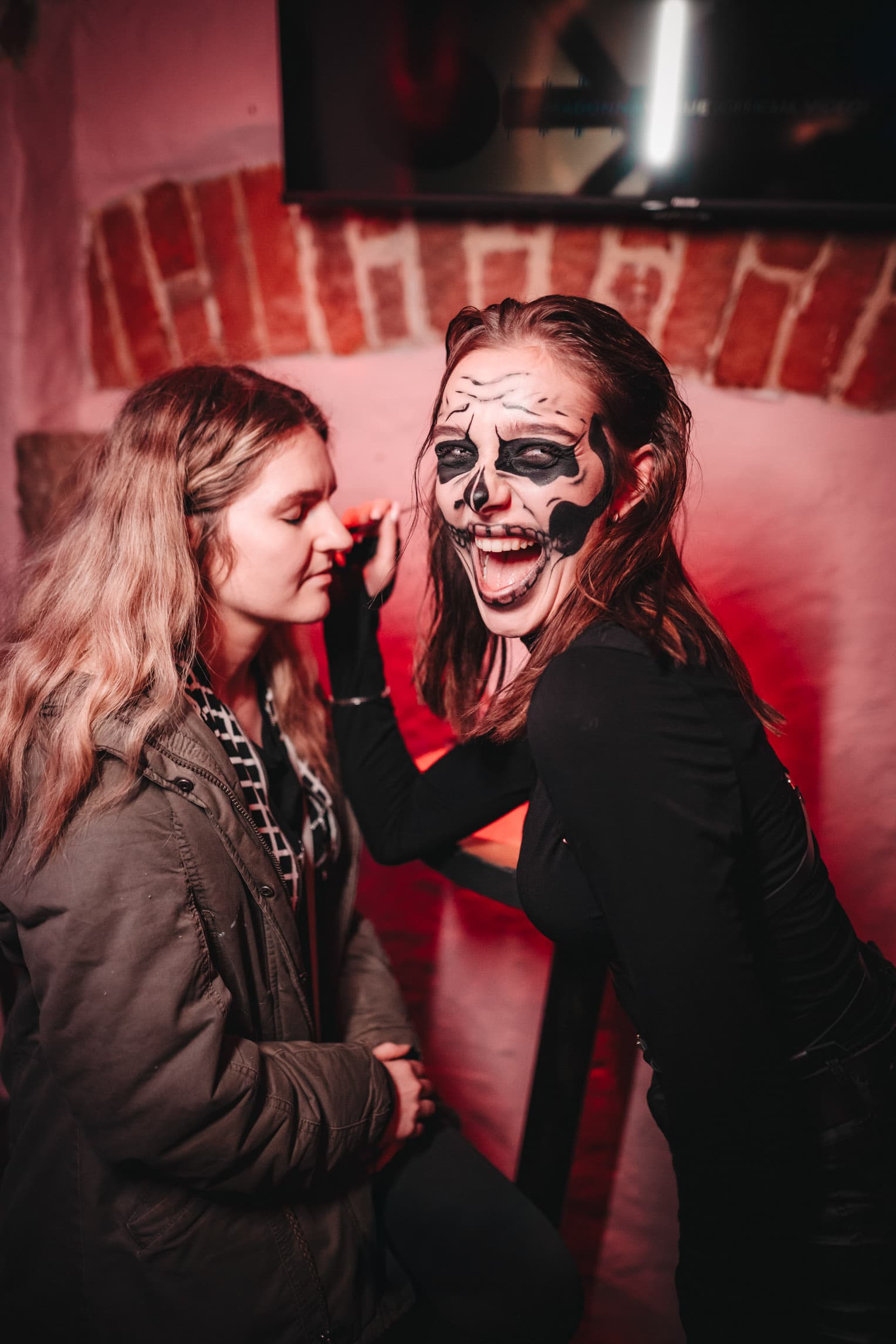 Guest laughing while having skull makeup applied before the Halloween crawl