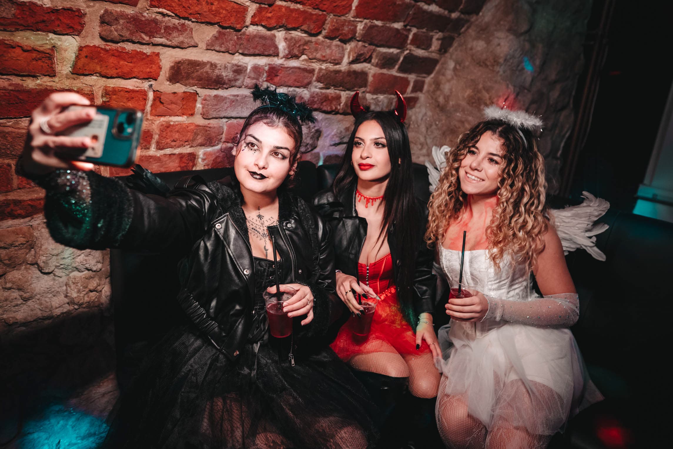 Three costumed friends taking a Halloween selfie with their drinks