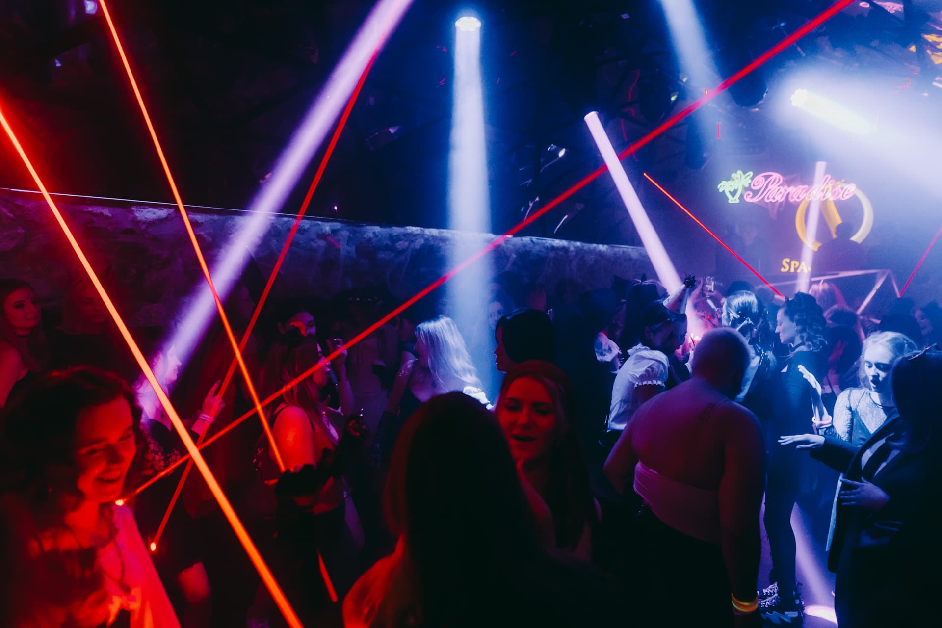 Halloween crowd dancing beneath red lasers in a Krakow club