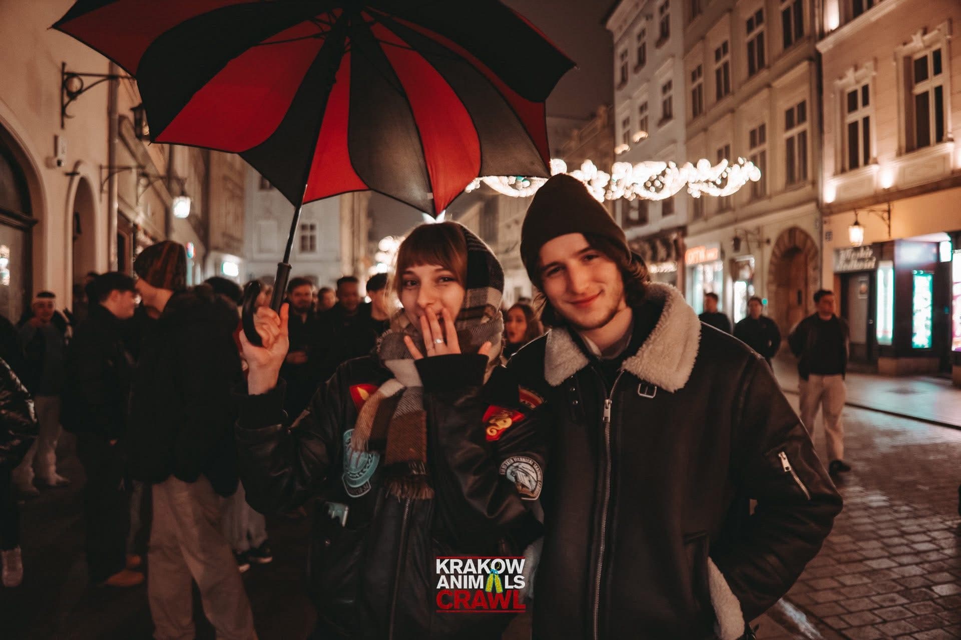 Guests following the black and red Krakow Animals Crawl umbrella through the Old Town